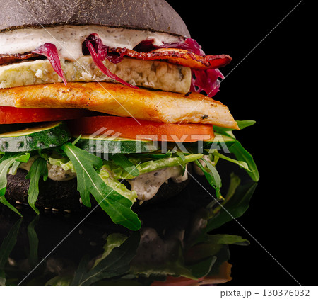 Unique black burger with various fresh vegetables served on a modern plate Unique black burger with various fresh vegetables served on a modern plate 130376032
