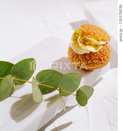 Unique pastry dessert with cream and pistachios on a white surface 130376036
