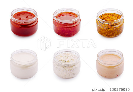 Various sauces and condiments in jars arranged on a white background 130376050