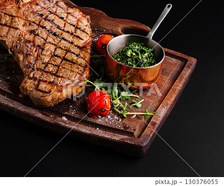 Grilled steak served with fresh herbs and tomatoes on wooden board 130376055