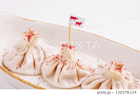 Unique dumplings garnished with red spice and a small flag 130376124