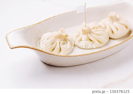 Dumplings or khinkali served elegantly on a white dish at a culinary event 130376125
