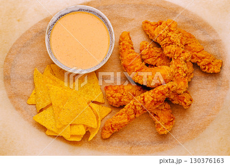 Crispy fried shrimp tenders with nachos and dipping sauce served on a platter Crispy fried shrimp tenders with nachos and dipping sauce served on a platter 130376163