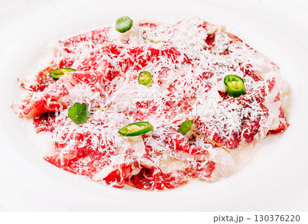 Premium raw beef carpaccio with garnishes and grated cheese on a plate 130376220