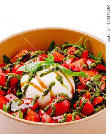 Burrata salad with cherry tomatoes and arugula drizzled with pesto sauce 130376264