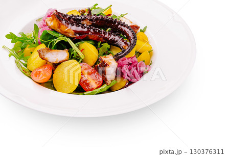 Delicious grilled octopus salad with fresh vegetables served in a white plate 130376311