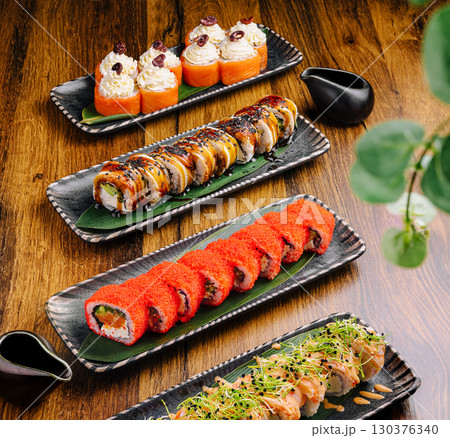 Delicious sushi assortment served on elegant black plates at a sushi restaurant Delicious sushi assortment served on elegant black plates at a sushi restaurant 130376340
