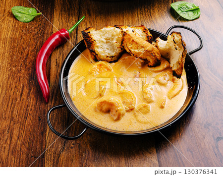 Delicious creamy curry served with crispy bread on a wooden table 130376341