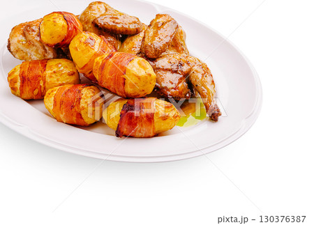 Delicious roasted chicken with bacon-wrapped potatoes served on a platter 130376387