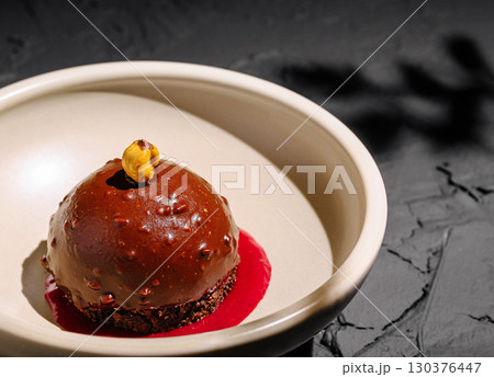 Decadent chocolate dessert served with raspberry sauce on elegant plate Decadent chocolate dessert served with raspberry sauce on elegant plate 130376447