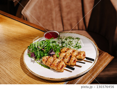 Delicious grilled pork skewers served with fresh salad and dipping sauce 130376456