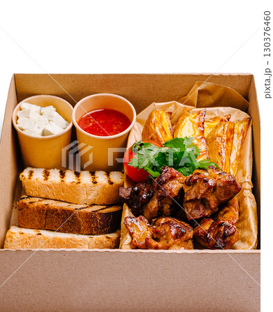 Delicious grilled meat platter served with sides in a cardboard box 130376460