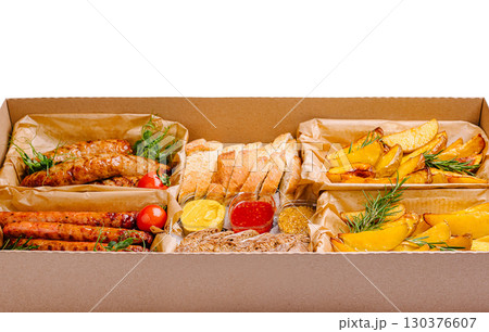Delicious assortment of grilled meats and sides in takeout box 130376607