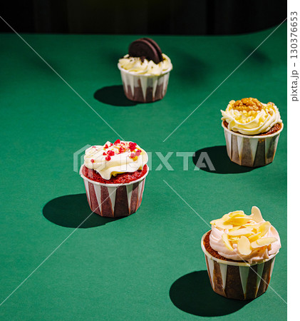 Delicious colorful cupcakes arranged on a green surface in a creative display 130376653