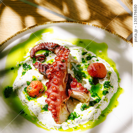 Grilled octopus served on a bed of creamy sauce with fresh herbs 130376680
