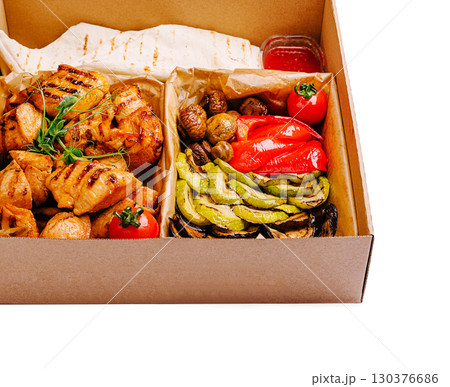 Grilled chicken and vegetable platter served in takeout container for dining 130376686