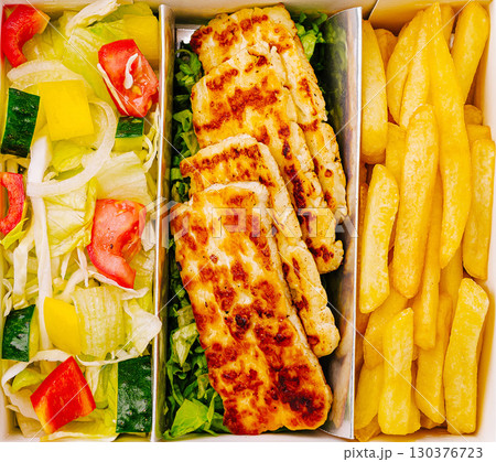 Delicious meal box with grilled cheese or chicken, fresh salad, and golden fries 130376723