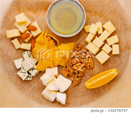 Cheese and snack platter with fruits and nuts on a wooden board Cheese and snack platter with fruits and nuts on a wooden board 130376747