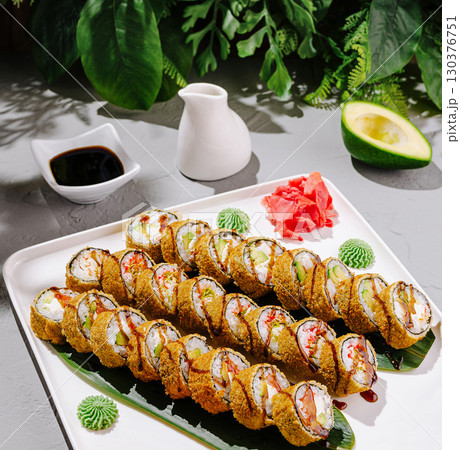 Sushi rolls arranged beautifully on a platter with fresh ingredients 130376751