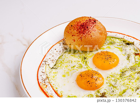 Brightly colored eggs served on a plate with bread and sauce 130376842