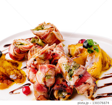 Delicious bacon-wrapped appetizers served with grilled fruits on a white plate Delicious bacon-wrapped appetizers served with grilled fruits on a white plate 130376874