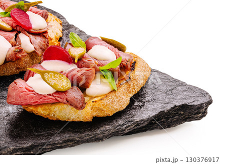 Delicious roast beef tartines served on a black slate platter Delicious roast beef tartines served on a black slate platter 130376917