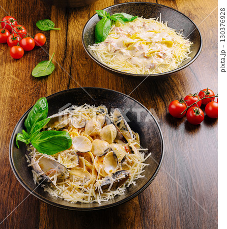 Gourmet pasta dishes served on wooden table with fresh ingredients 130376928