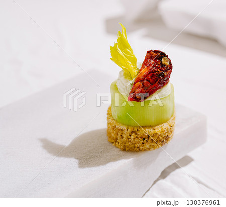 Elegant cucumber appetizer with green herb cream and dried tomato Elegant cucumber appetizer with green herb cream and dried tomato 130376961