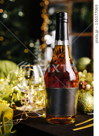 Festive table arrangement with a bottle of liquor and holiday decorations Festive table arrangement with a bottle of liquor and holiday decorations 130377069