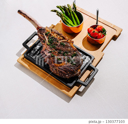 Juicy ribeye steak served with roasted tomatoes and grilled asparagus Juicy ribeye steak served with roasted tomatoes and grilled asparagus 130377103