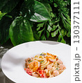 Delicious shrimp pasta served in a white bowl with green foliage background 130377111