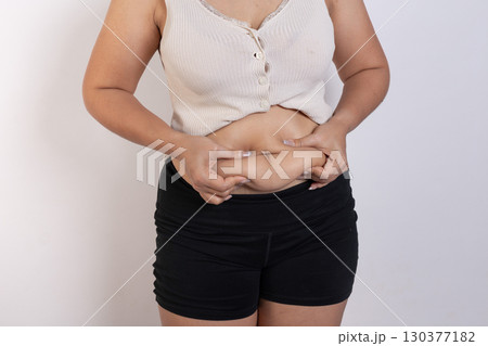 Overweight woman hand pinching excessive belly fat on gray background, Healthy concept 130377182