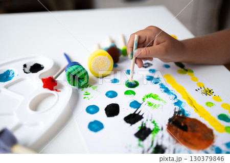 Child painting with bright colors using sponge brushes on white canvas Child painting with bright colors using sponge brushes on white canvas 130379846