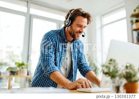 Businessman in headset providing assistance to a client in a modern workspace during daytime 130381377