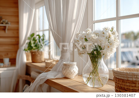 Bright sunlight streaming through windows with white curtains and blooming flowers in a cozy space 130381407