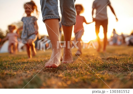 Walking barefoot on grass in a sunny park with children during evening hours Walking barefoot on grass in a sunny park with children during evening hours 130381552