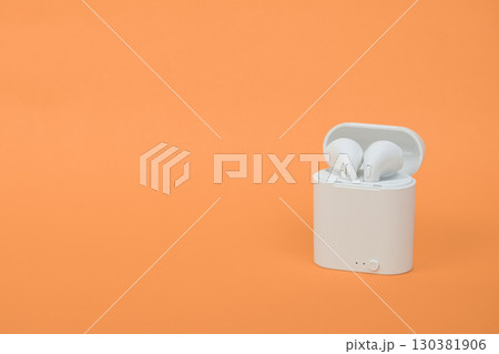 Modern wireless earbuds headphones isolated on orange background with clipping path. Wireless Earbuds Stereo or Earphones in charging case on colored background with copy space. Modern wireless earbuds headphones isolated on orange background with clipping path. Wireless Earbuds Stereo or Earphones in charging case on colored background with copy space. 130381906