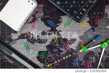 School accessories on dark background. Flat lay with stationery objects on world map background. Back to school concept. 130382004