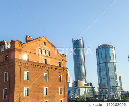 The contrast of an old brick building with modern skyscrapers in the background. The concept of the city's development, a combination of the past and the future. 130382006