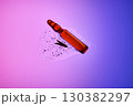 An ampoule with serum in its texture on a purple background with a leaf. 130382297