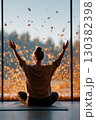 Stretching and embracing tranquility in a serene indoor space surrounded by autumn leaves 130382398