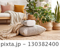 Headset resting on a yoga cushion in a cozy living room filled with plants and soft textiles 130382400