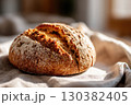 Grain sourdough bread resting on a linen cloth in a cozy kitchen setting 130382405