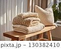 Cotton throws gracefully arranged on a natural wood bench in a sunlit room 130382410