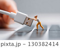 Tiny figure struggles to connect USB cable on computer keyboard during creative setup 130382414