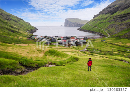Tourist In Red Jacket Looking At Tjornuvik Village And Ocean, Faroe Islands 130383587