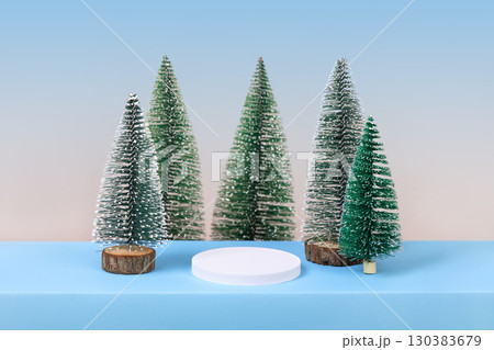 Winter background with cylindrical empty podium display for promotions and for showing product decorate. Stage pedestal or platform between Xmas trees on blue table. Merry Christmas celebration. Winter background with cylindrical empty podium display for promotions and for showing product decorate. Stage pedestal or platform between Xmas trees on blue table. Merry Christmas celebration. 130383679