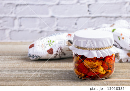 Cherry dried tomatoes in a jar with herbs and oil. Cherry dried tomatoes in a jar with herbs and oil. 130383824