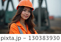 Asian female oilfield technician is at work at the pumpjack. 130383930