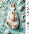 Easter Bunny with a pink egg on among flowers on blue background. 130383931
